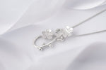Load image into Gallery viewer, Silver necklace with floral pendant on a white fabric background
