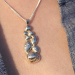 Load image into Gallery viewer, A silver pendant necklace with a chain, displayed on a person's neckline.
