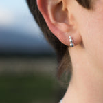 Load image into Gallery viewer, Close-up of an ear wearing a silver earring with a blurred natural background
